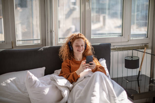 istock Young woman using a mobile phone in bed 1256720310