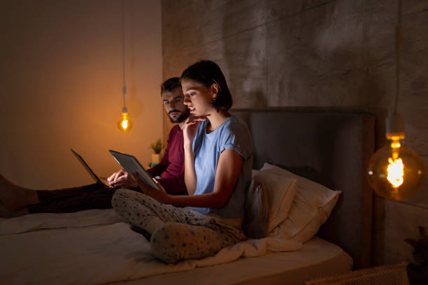 istock Couple in bed working overtime 1256720314