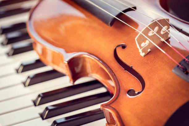 violino em cima de teclas de piano fundo - piano piano key orchestra close up - fotografias e filmes do acervo