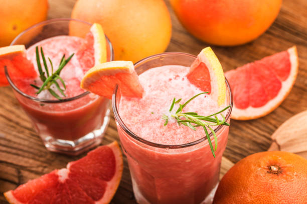 grapefruitsaft mit rosmarin und eis in einem glas auf dem tisch. erfrischender sommercocktail - glass ice tonic water frozen stock-fotos und bilder