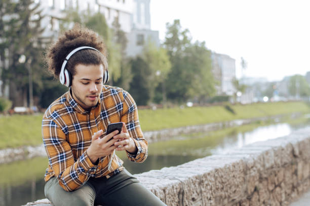 istock Young man listening podcasts by the river 1256724108