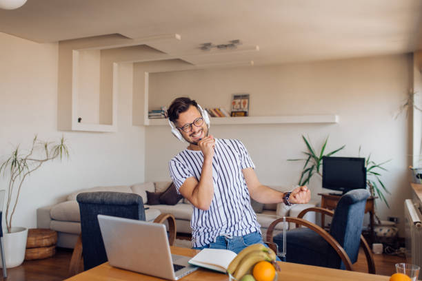 istock Excited young man dancing and singing at home 1256724147