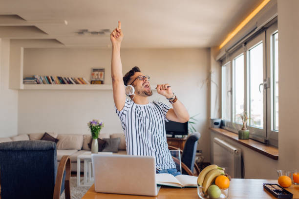 joven emocionado haciendo su propia fiesta loca en casa - regocijo fotografías e imágenes de stock