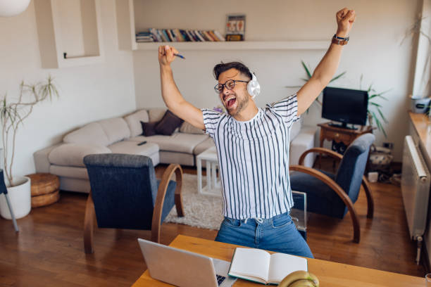 istock Young man dancing and singing after work at home 1256724176