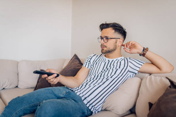 istock Young man watching TV at home 1256724240