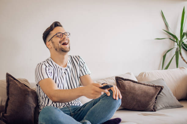 istock Young man watching something funny on TV and laughing 1256724249