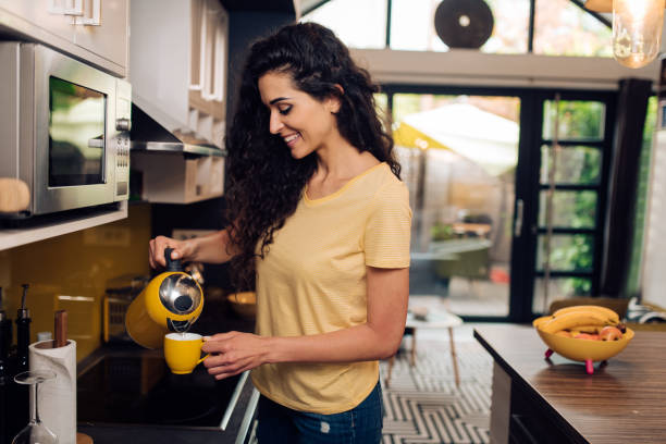 istock Happy woman making morning coffee at her kitchen 1256725621