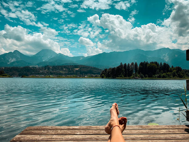 Digital Detox on a Jetty at Lake Faak in Carinthia, Austria Digital Detox at Lake Faak, Austria – getting away from it all with a lake and mountain view at its best legs crossed at ankle stock pictures, royalty-free photos & images