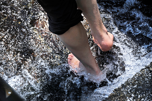 Male feet during a cold water Kneipp treatment in a water stream.