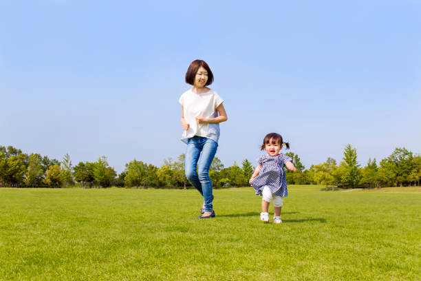 istock Mather and little daughter running on green grass square against blue sky 1256731477