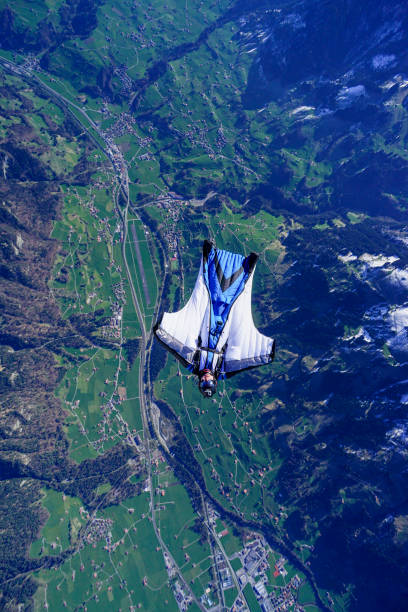 istock Wing suit soars above mountain landscape 1256731613