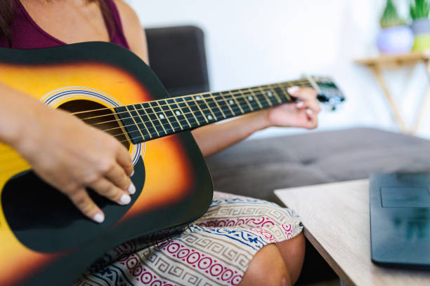 istock Young women playing on a quitar at home learning from a computer 1256732152