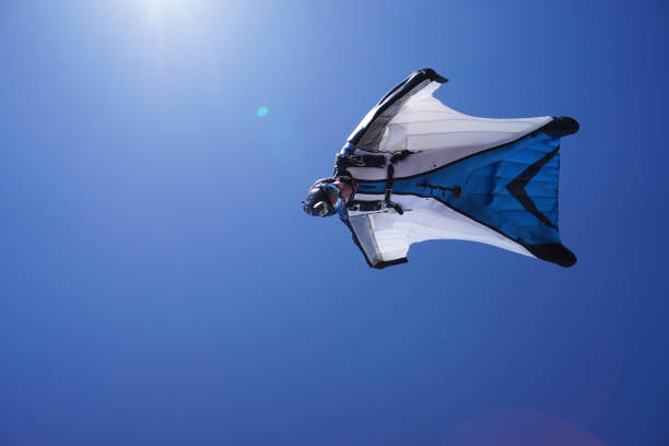 le costume d’aile s’élève au-dessus du paysage de montagne - wingsuit photos et images de collection