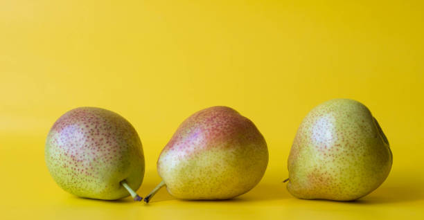 istock Three green red  fresh pears isolated on  yellow background. 1256733386