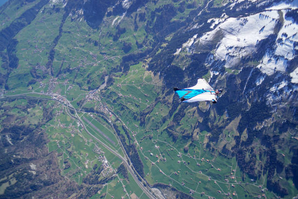 istock Wing suit soars above mountain landscape 1256733937