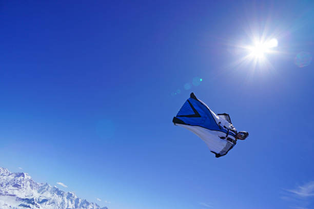 istock Wing suit soars above mountain landscape 1256736481