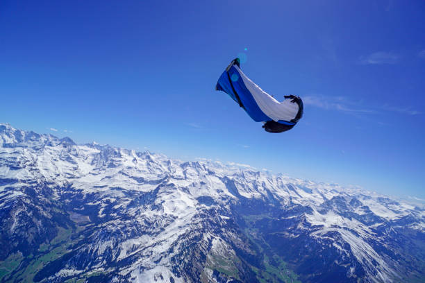 istock Wing suit soars above mountain landscape 1256736890