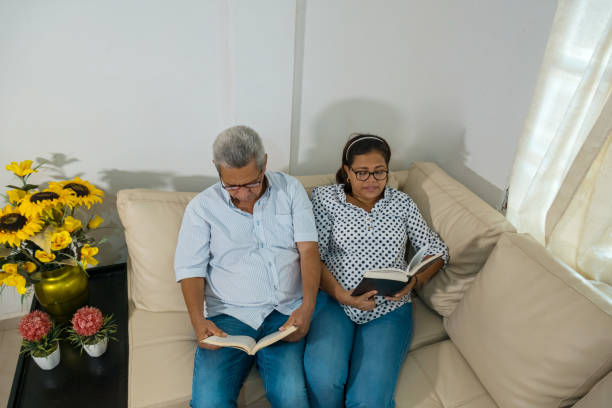 ソファでリラックスして本を読む素敵な年上のカップル - home interior entertainment sofa men ストックフォトと画像