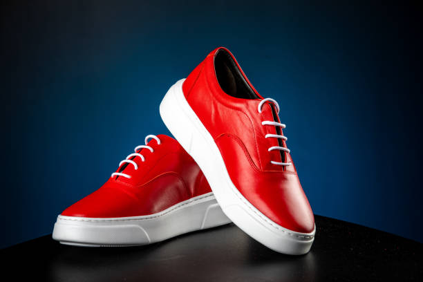istock mens red leather shoes with white soles on blue background 1256739717