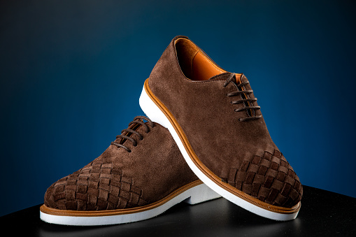 a pair of men brown suede dress shoes on blue background