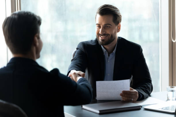 istock Smiling young handsome businessman shaking hands with male confident partner. 1256739905
