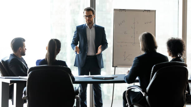 istock Confident male leader coach instructing interested diverse teammates. 1256739941