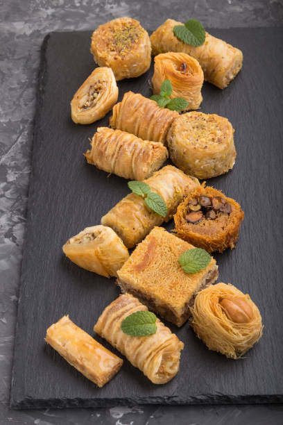 istock traditional arabic sweets (kunafa, baklava) on a black slate board on a black concrete background. side view, close up. 1256740975