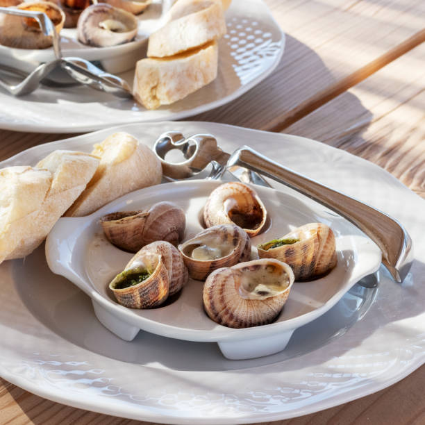 istock Plate with cooked snails in a rustic restaurant closeup. 1256741244