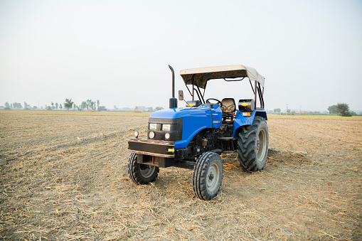 Sandwich, Massachusetts, USA- October 28, 2023-  A mature bearded man plows a agricultural field at Gopal Farm using an antique grey and red Ford tractor on a late October morning on Cape Cod.