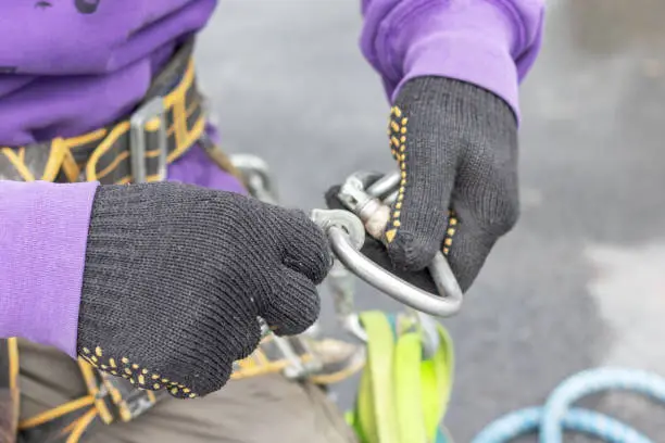 Worker fixes a climbing equipment before descending from the roof. High-altitude works.