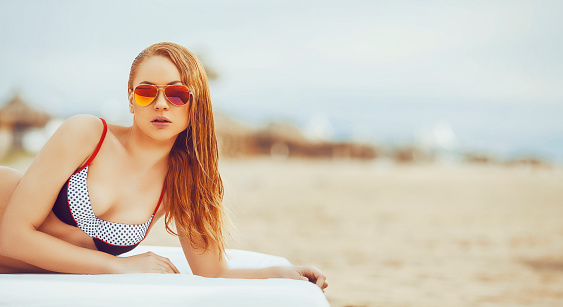 Beautiful woman with bikini tanning under the sun on the beach