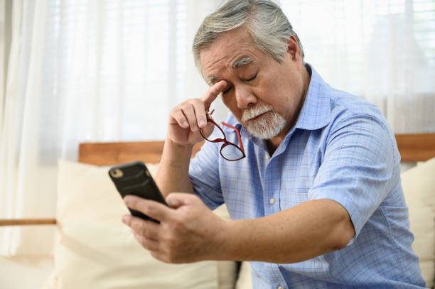 노인 라이프 스타일 ��건강 문제 개념 : 노인 아시아 남자의 초상화 사진은 스마트 폰에서 메시지를 읽으려고 눈 길먼 문제가 있습니다. - pain human eye senior adult men 뉴스 사진 이미지