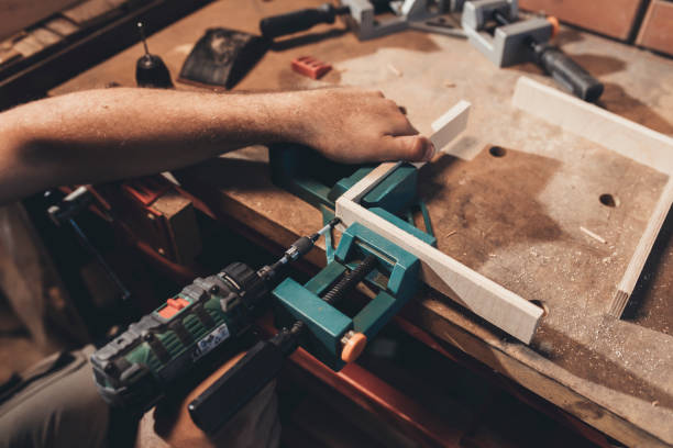 istock Hands of a Anonymous Carpenter Using a Power Drill to Make Furniture in his Workshop 1256745912