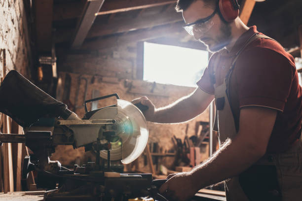 istock Carpenter Cutting Wood on a Mitre Saw at his Workshop 1256745920