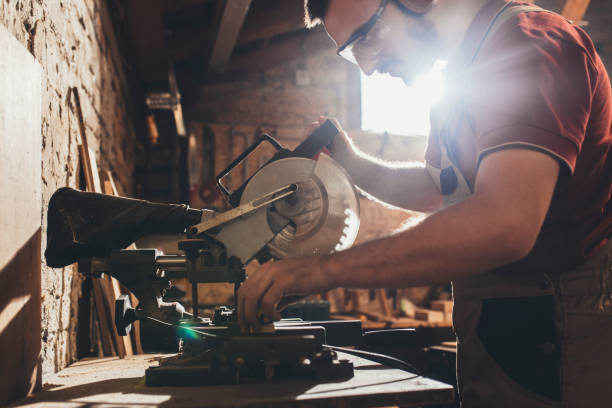 istock Carpenter Cutting Wood on a Mitre Saw at his Workshop 1256745925