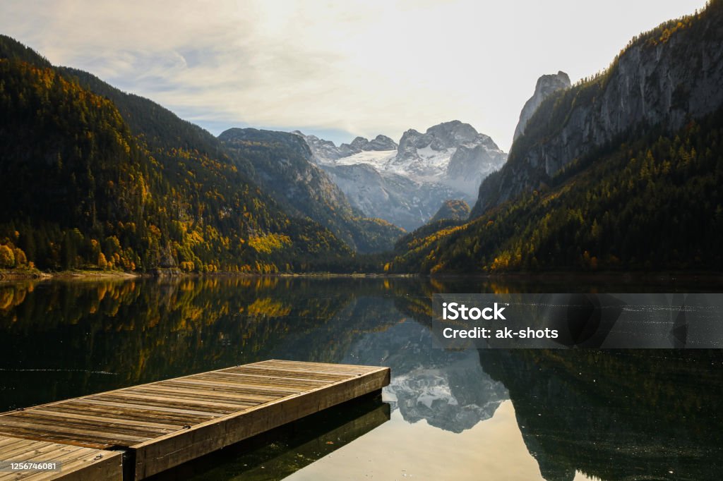 Scenic view of Lake Gossau with a Pier and Dachstein Glacier in the background Scenic view of reflecting  Gosausee / Gosau Lake with a Pier and with Dachstein Gletcher / Dachstein Glacier in the background Dachstein Mountains Stock Photo