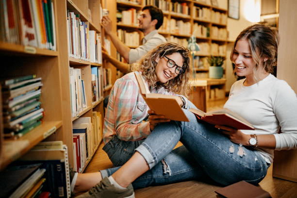 istock Friends reading book in library together 1256746331