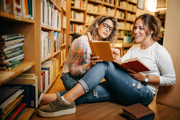 istock Friends reading book in library together 1256748940