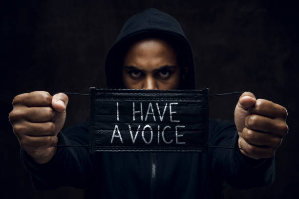 Stop racism Afroamerican man wearing hoodie holds black facial mask with inscription I have a voice. Anti-racism concept. i cant breathe photos stock pictures, royalty-free photos & images