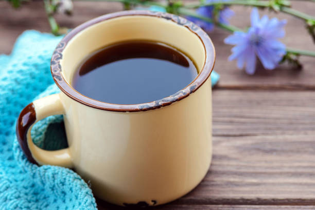 une boisson de guérison utile de racine de chicorée dans une tasse en métal sur la table. - succory photos et images de collection