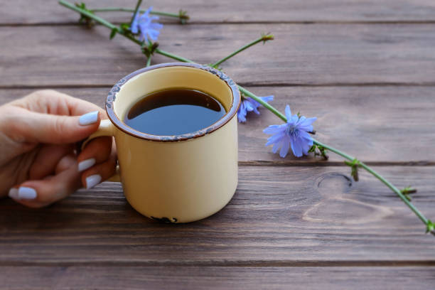 un'utile bevanda curativa dalla radice di cicoria in una tazza di metallo sul tavolo. alternativa al caffè. - succory foto e immagini stock