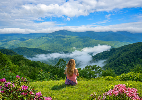 Woman sitting on top of the mountain on summer trip.