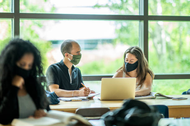 istock Small group of mixed ethnicity students wearing masks in a classroom 1256757829