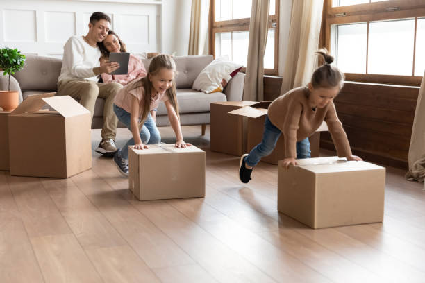 istock Two daughters helping parents on moving day, pushing cardboard boxes 1256762249