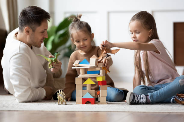 istock Happy father playing with two daughters playing on warm floor 1256762258