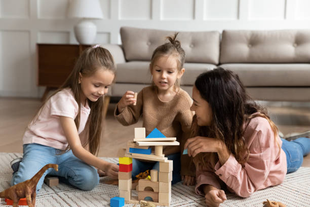 istock Happy young mother playing with two daughters on warm floor 1256762280