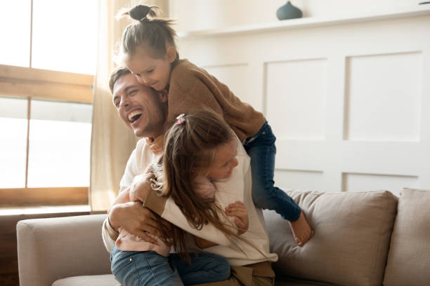 istock Excited father having fun with two little daughters at home 1256762298