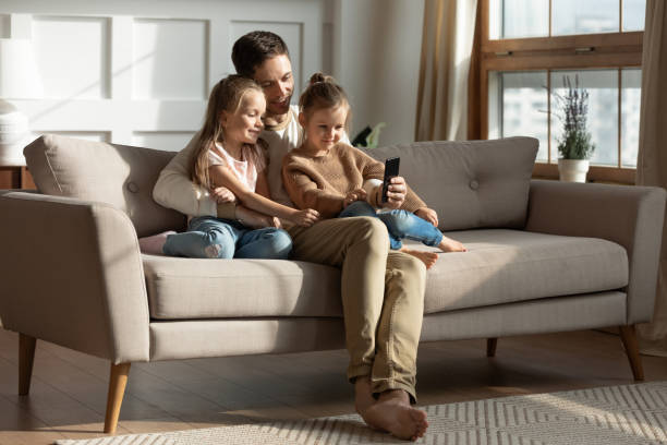 istock Smiling father with two little daughters using phone 1256762327