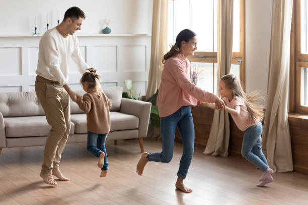 happy parents dancing with little daughter in living room - child party group of people little girls imagens e fotografias de stock