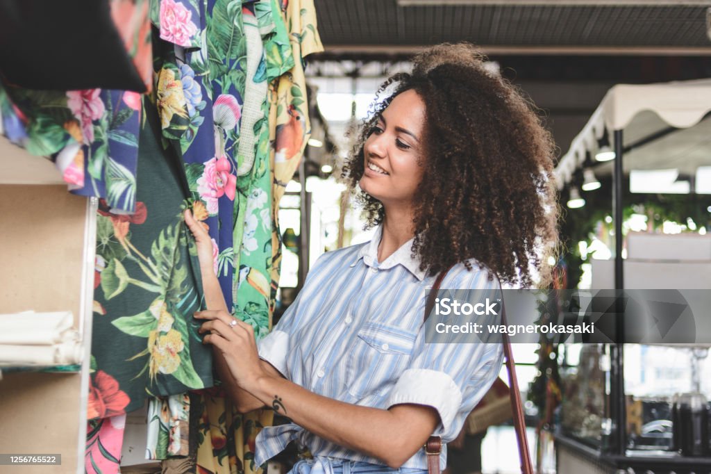 Young woman shopping clothes in a market stall Thrift Store Stock Photo